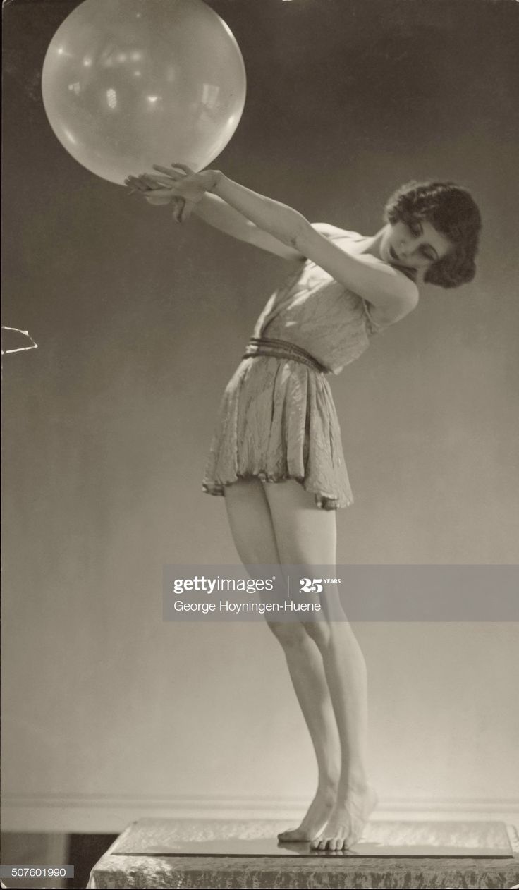 a young woman holding a balloon in her hand and standing on a pedestal with one leg up