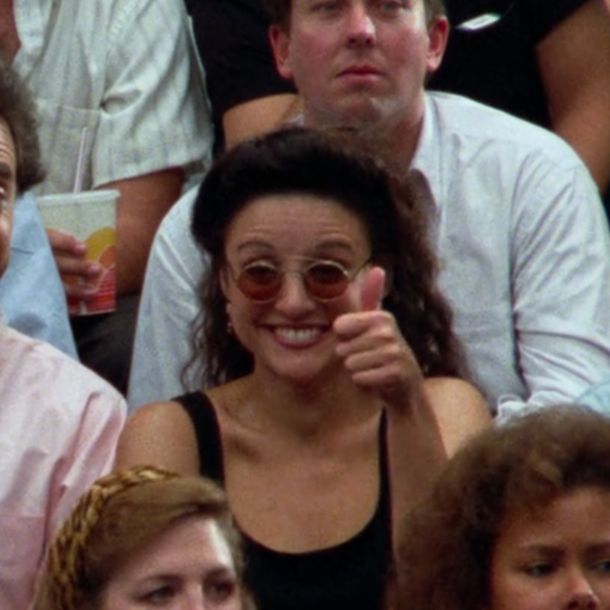 a woman wearing sunglasses sitting next to a man in front of a group of people