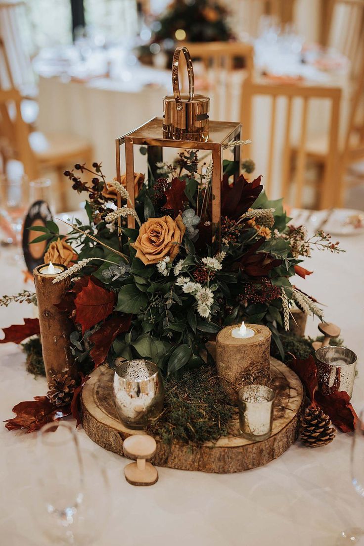 an arrangement of flowers and candles on a wooden stand at a wedding breakfasteon table