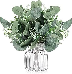 a vase filled with green leaves and white flowers