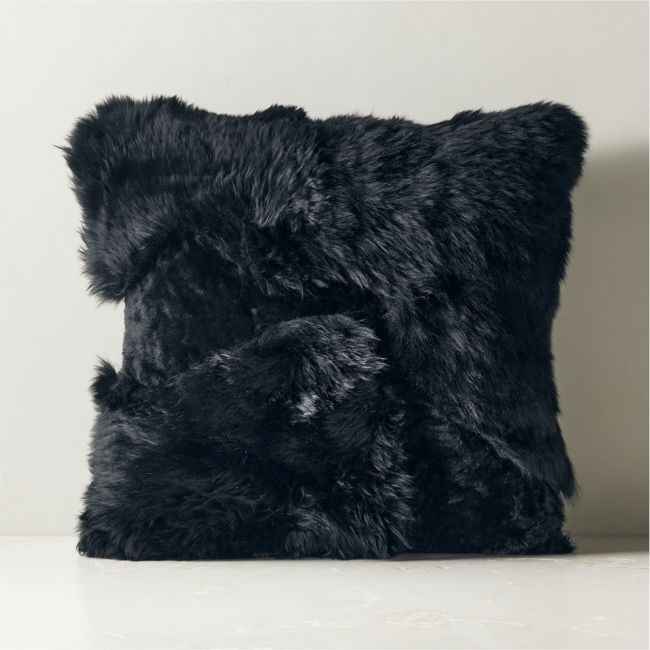 a black furry pillow sitting on top of a white table next to a wall and window