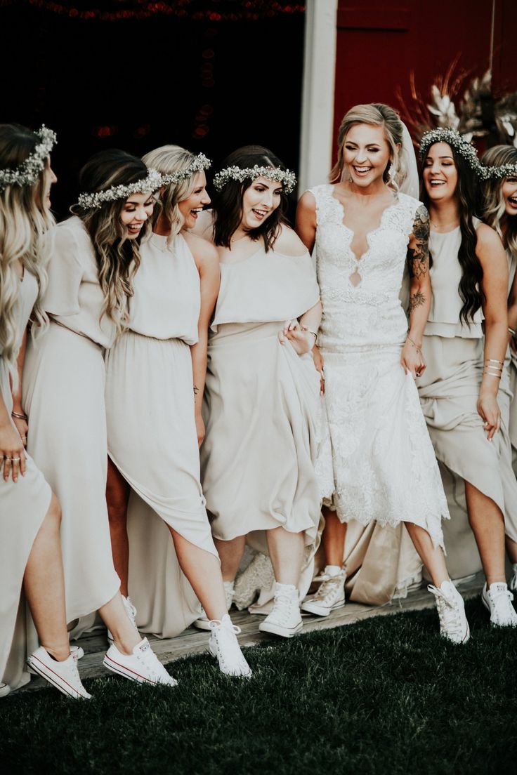 a group of women standing next to each other wearing white dresses and flower crowns on their heads