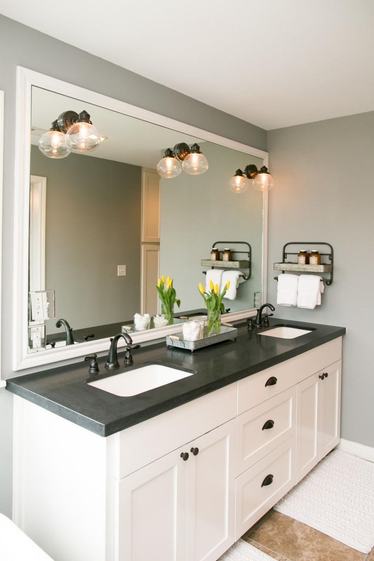 the bathroom has two sinks and black granite countertops with lights on them, along with a large mirror