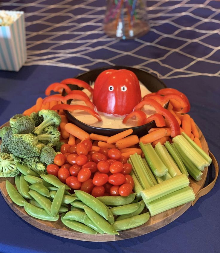 a platter with vegetables and an octopus on the top is sitting on a blue table cloth