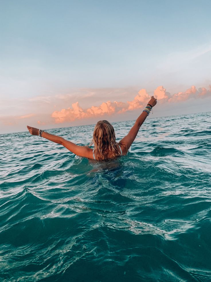 a woman floating in the ocean with her arms outstretched