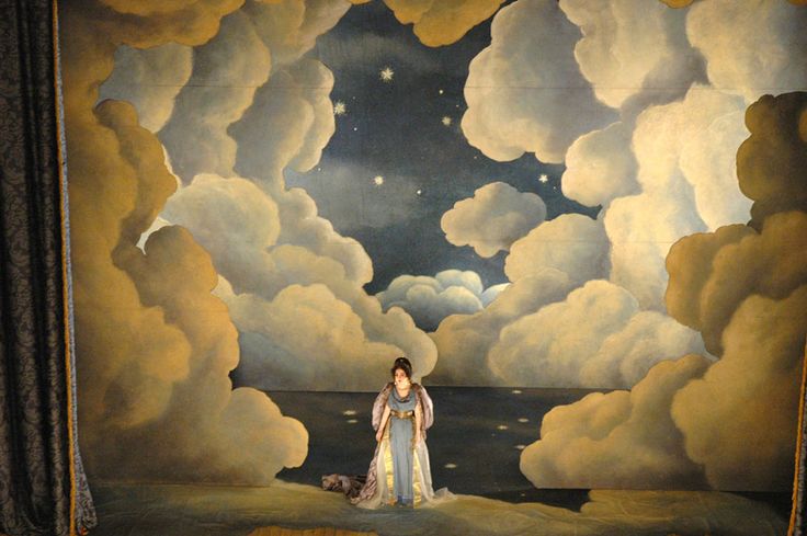 a woman standing in front of a painting with clouds and the moon above her head