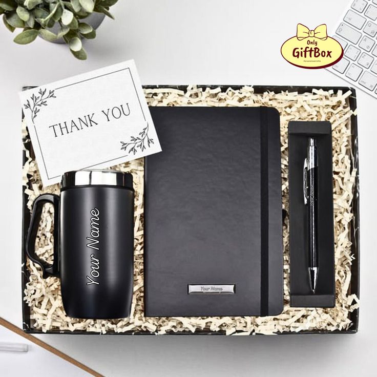 an open gift box containing a black coffee mug, pen and notepad with thank you written on it