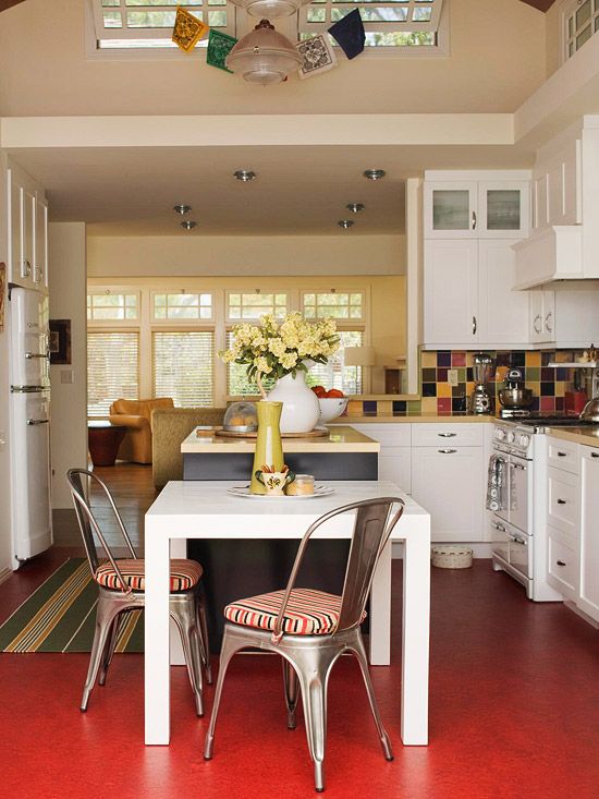 a kitchen with red flooring and white cabinets is pictured in this image, there are two chairs at the center of the table