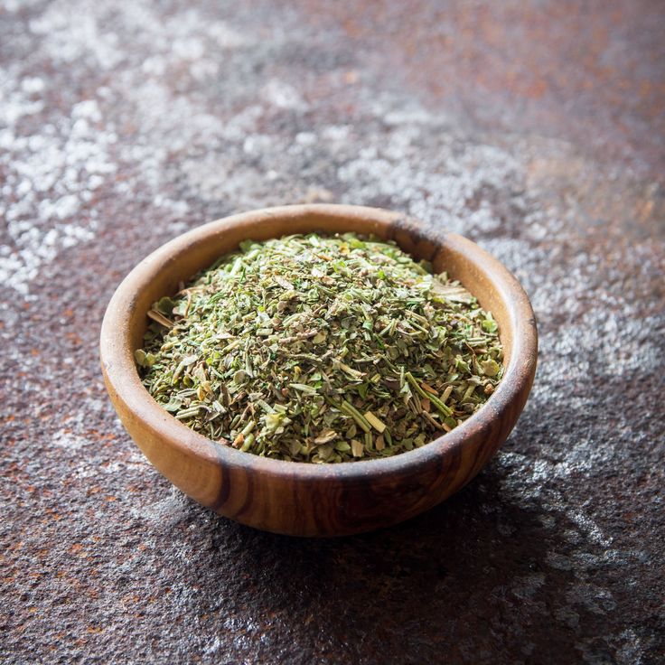 a wooden bowl filled with dried herbs on top of a table