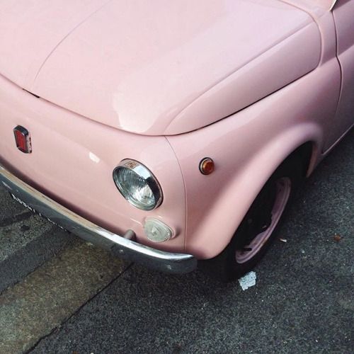 an old pink car is parked on the side of the road