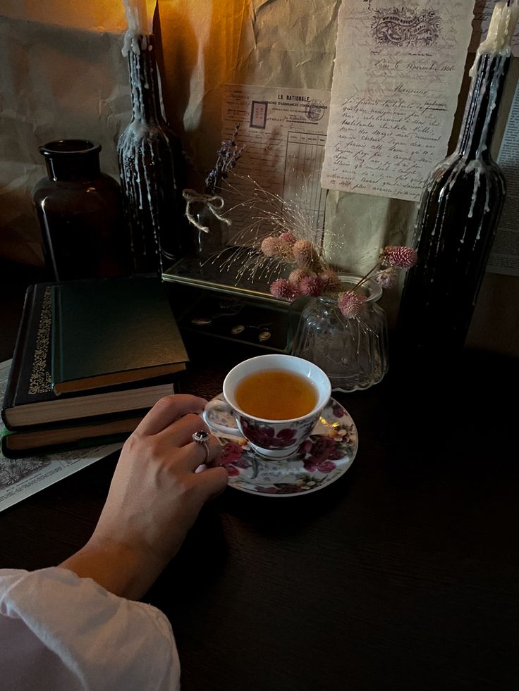 a person sitting at a table with a cup of tea in front of some books