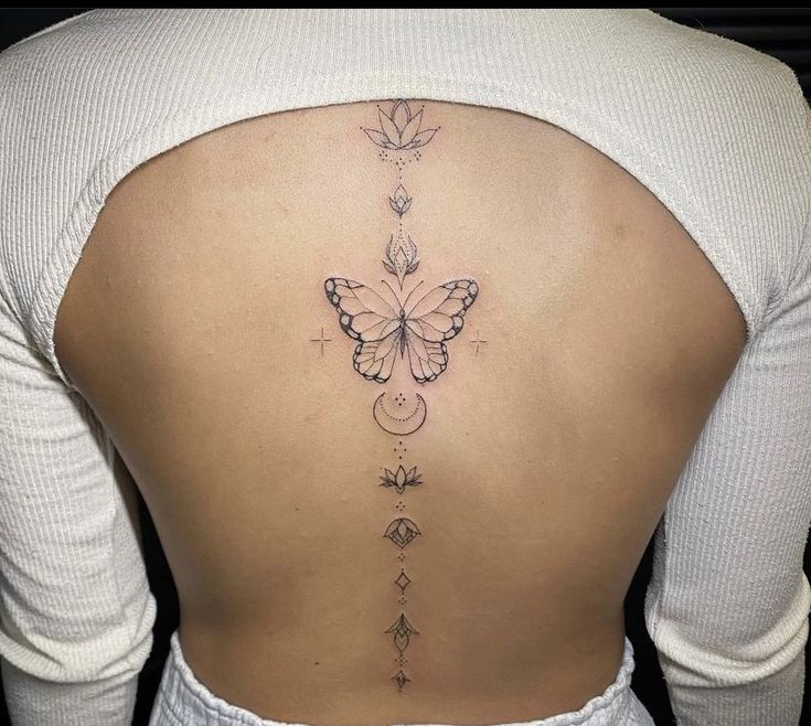 a woman's back with a butterfly tattoo on her lower back and an arrow in the middle