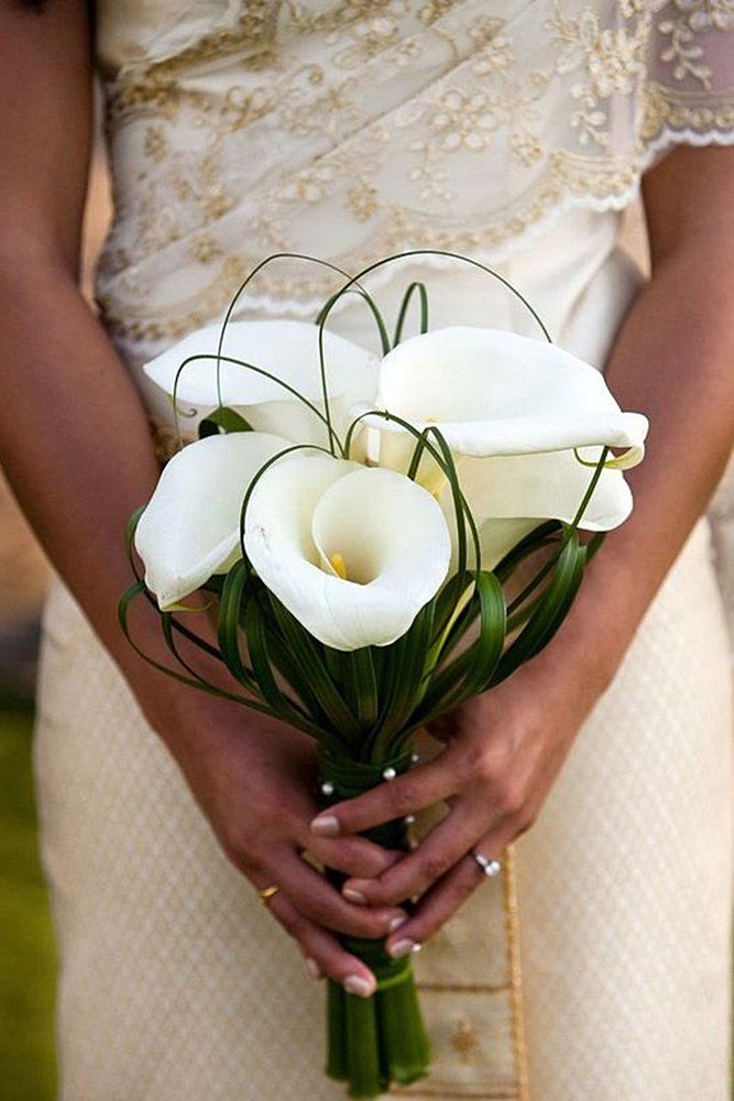 a woman holding a bouquet of white flowers in her hands and wearing a wedding dress