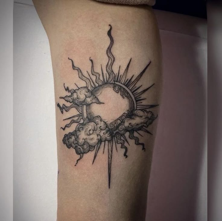 a sun and clouds tattoo on the right thigh with lightning coming out from behind it