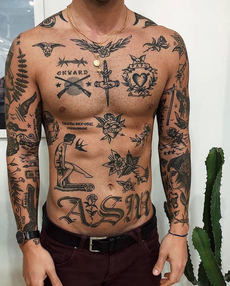 a man with lots of tattoos on his body and chest standing in front of a cactus