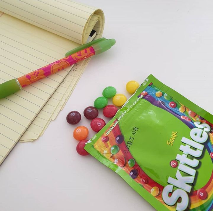 a bag of gummy bears next to a notepad and pencil