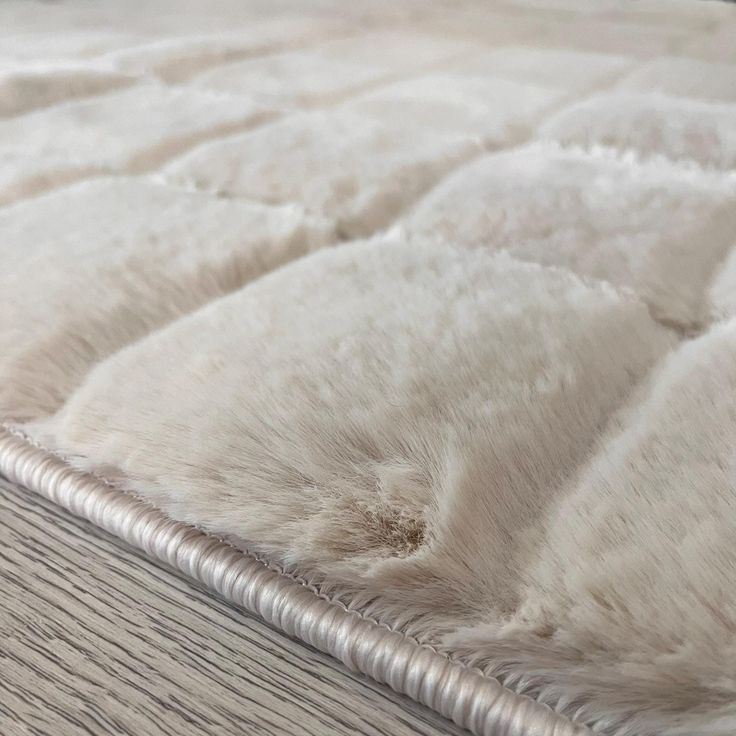 a close up view of an unmade bed with white fur on the top and bottom