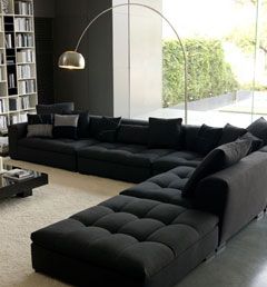 a living room filled with furniture and a large book shelf next to a woman standing in the doorway