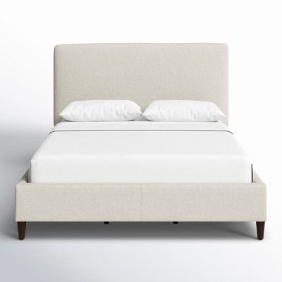 a bed with white linens and pillows on it's headboard is shown