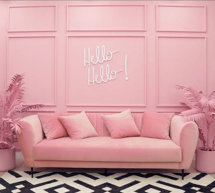 a pink couch sitting in front of a wall with hello hello written on the side