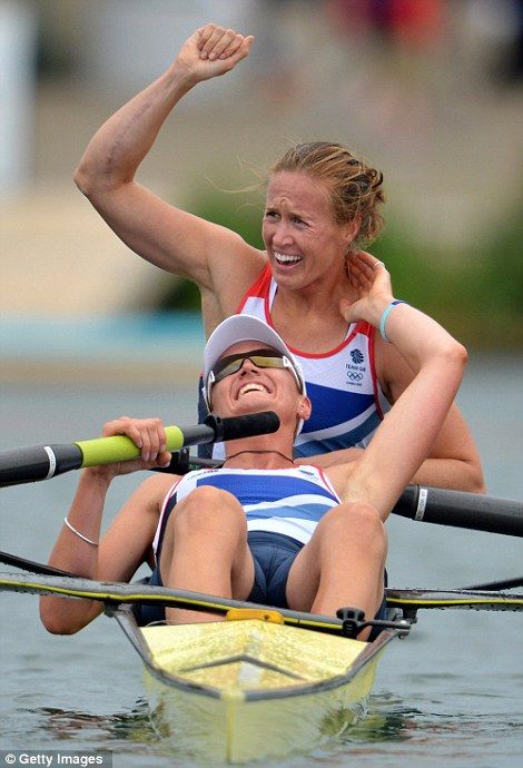 two women are rowing on the water and one is raising her arm in the air