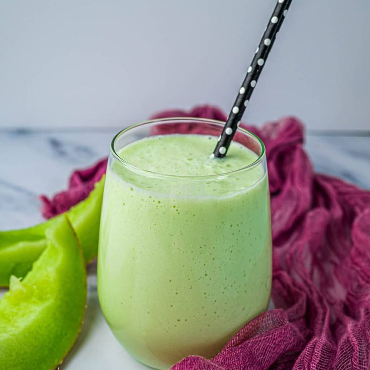 a green smoothie in a glass with a black straw