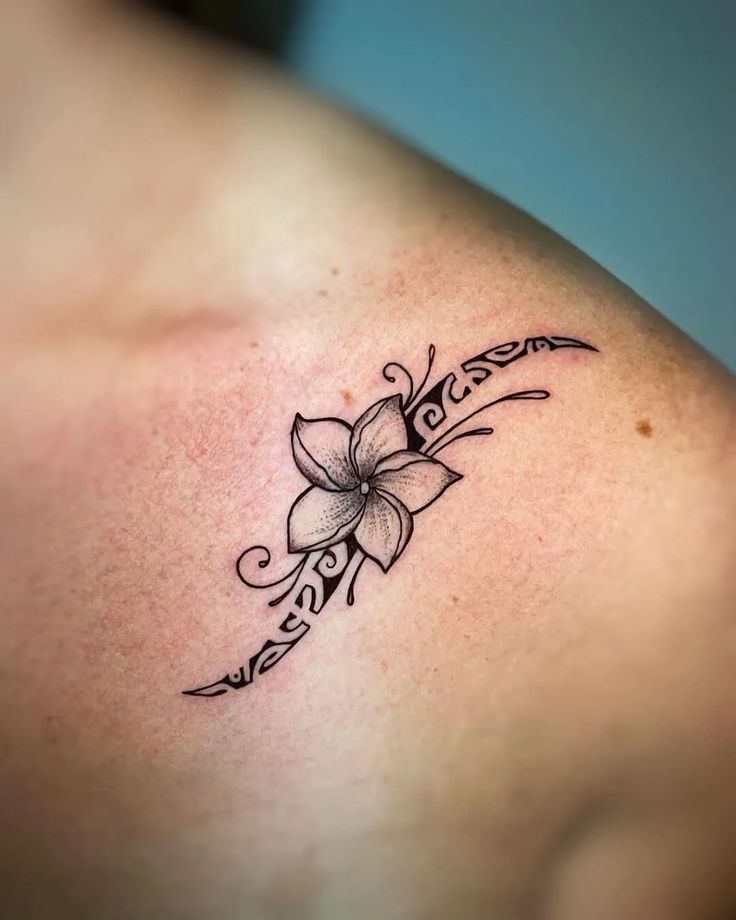 a tattoo on the back of a woman's shoulder with a flower in it