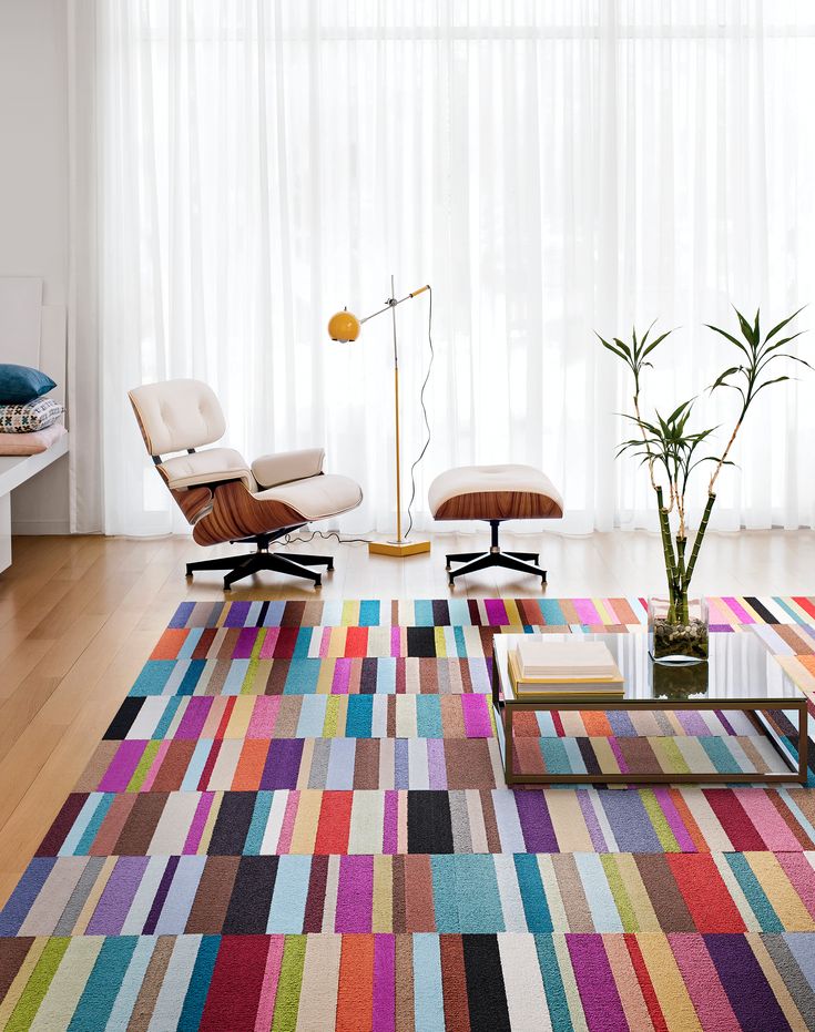 a living room with colorful rugs, chairs and a plant in the center area