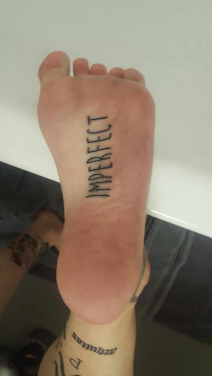 a person's foot with the words written on it and an upside down tattoo