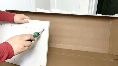 a person is holding a pair of pliers in front of a cardboard box with holes