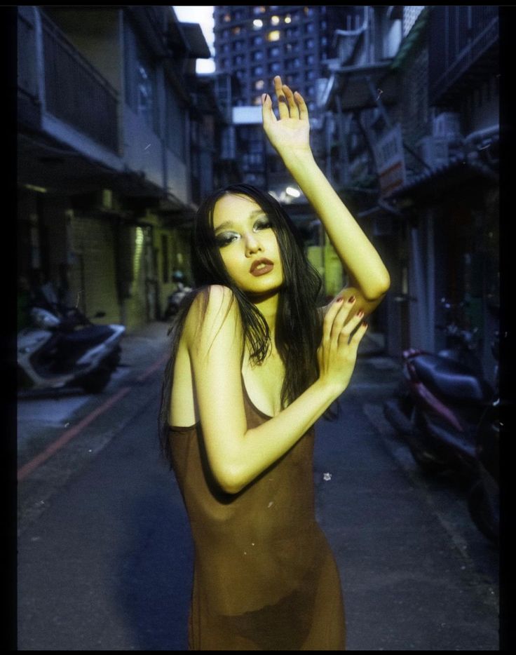 a woman standing in the middle of an alley way with her hand on her head