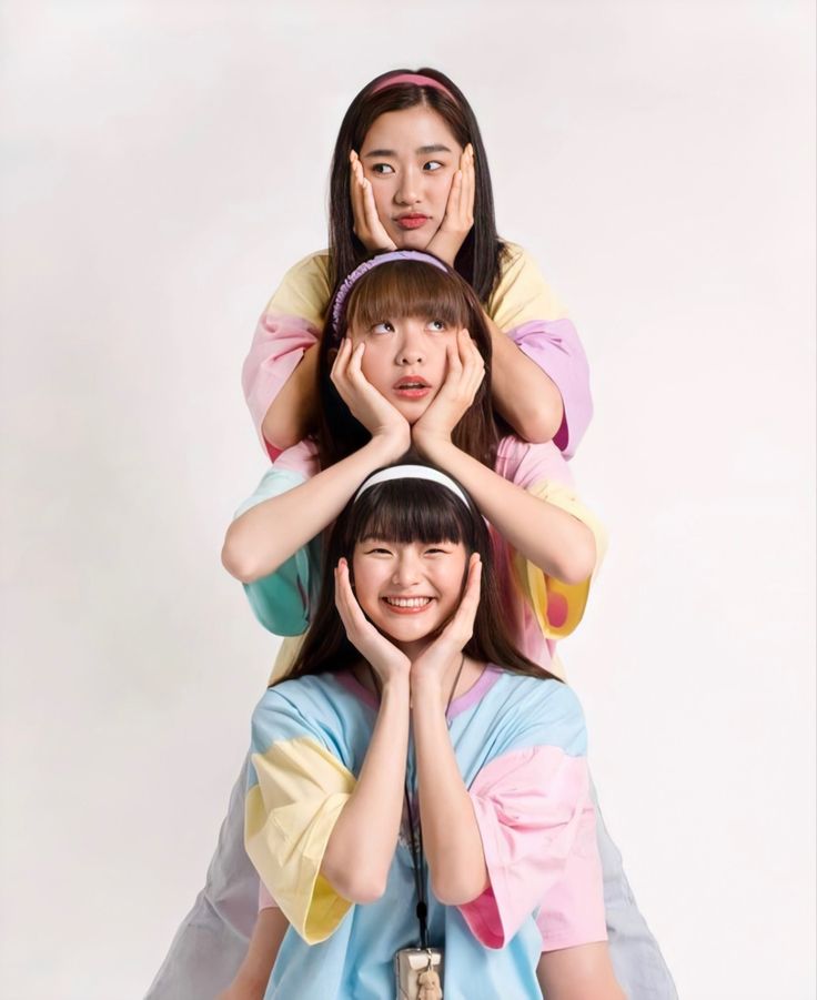 three young women are sitting on top of each other in front of a white background