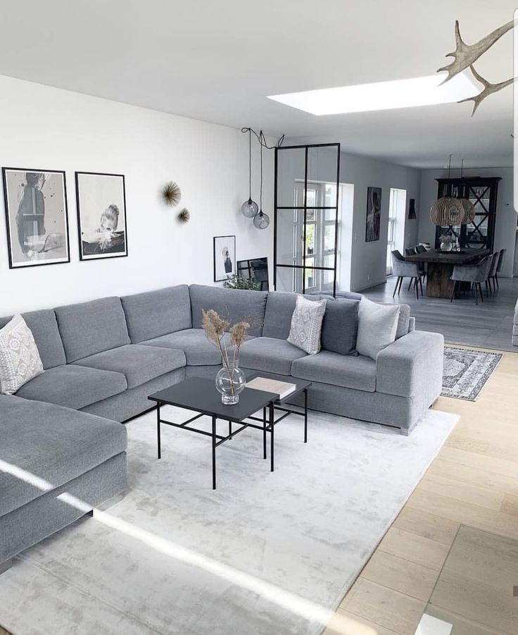 a living room with grey couches and pictures on the wall above it, along with a coffee table