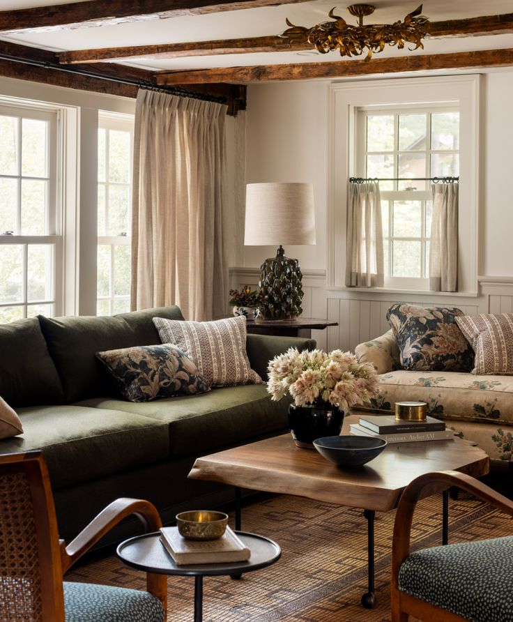 a living room with couches, chairs and coffee table in front of two windows