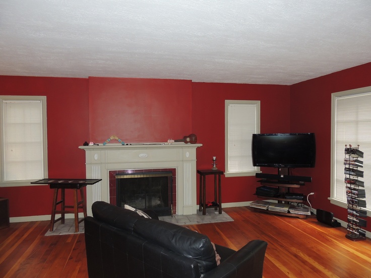 an empty living room with red walls and wood flooring is seen in this image