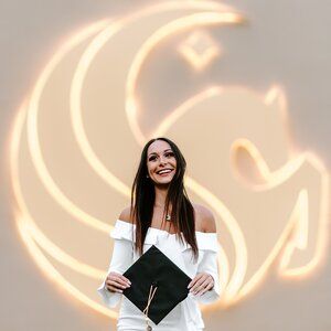 a woman standing in front of a wall holding a black and white clutch bag with her hands on her hips