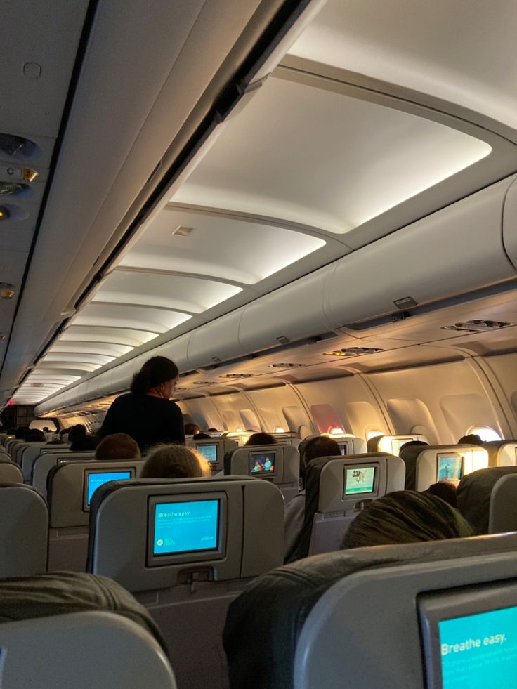 the inside of an airplane with people sitting in seats and on televisions, all looking at their screens