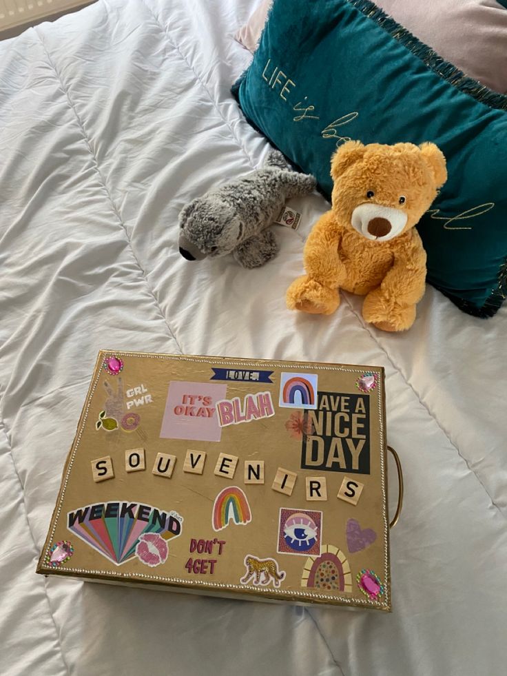 two stuffed animals on a bed next to a bag with stickers all over it