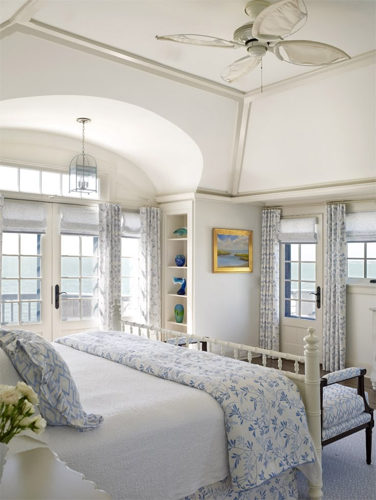 a large white bed sitting in a bedroom next to two windows