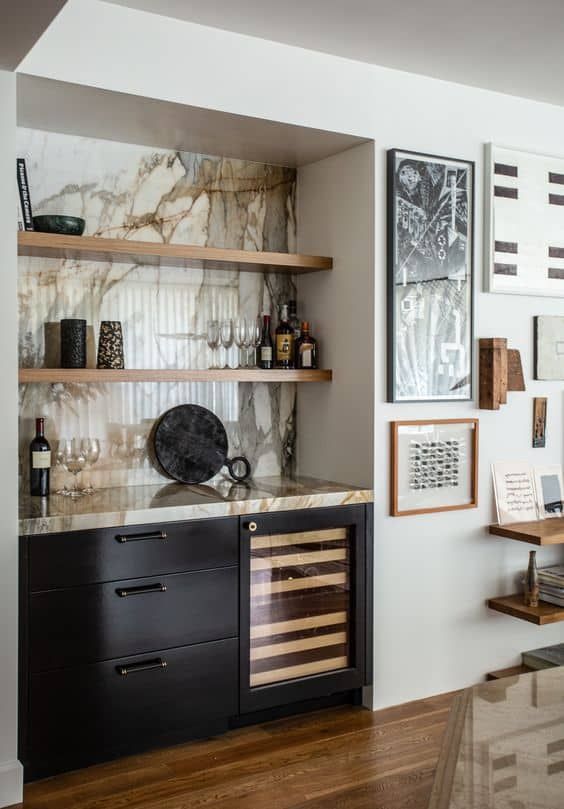 a kitchen with marble counter tops and wooden shelves on the wall, along with wine bottles