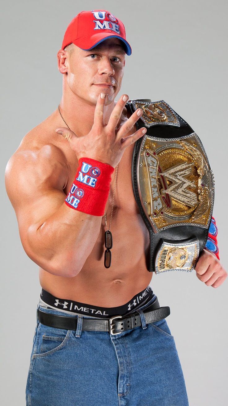 a man in jeans and a red hat holding a wrestling ring with his finger up