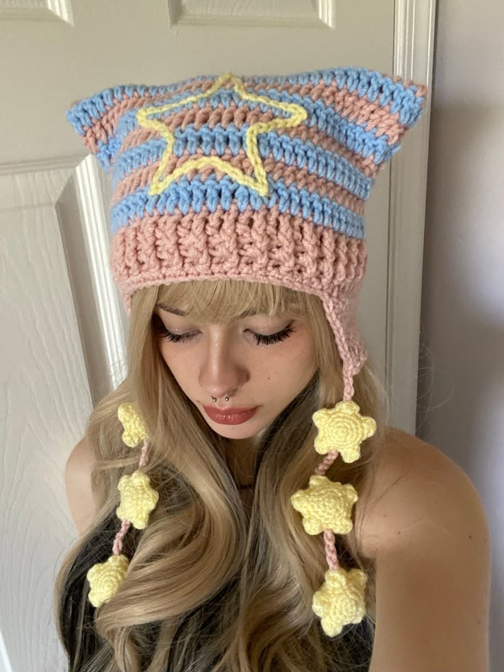 a woman wearing a crocheted hat with pom poms