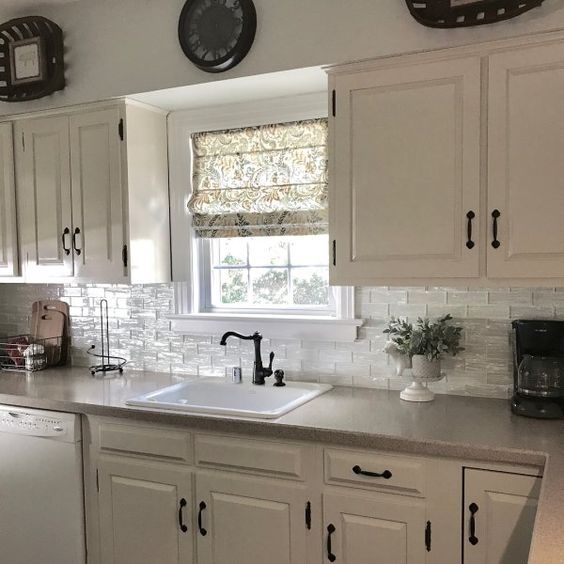 a kitchen with white cabinets and black clock on the wall above the sink is shown