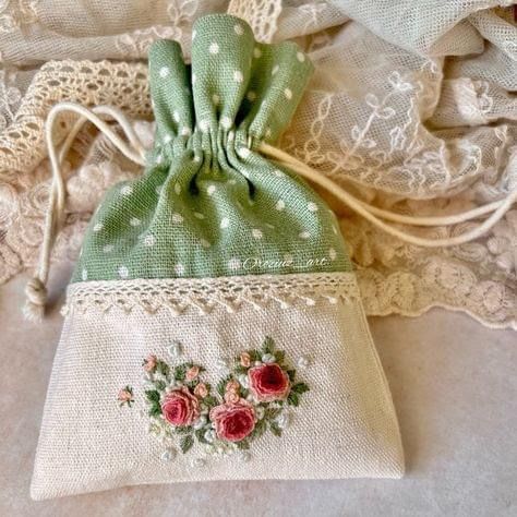 a small bag with flowers on it sitting on top of a lace covered table cloth