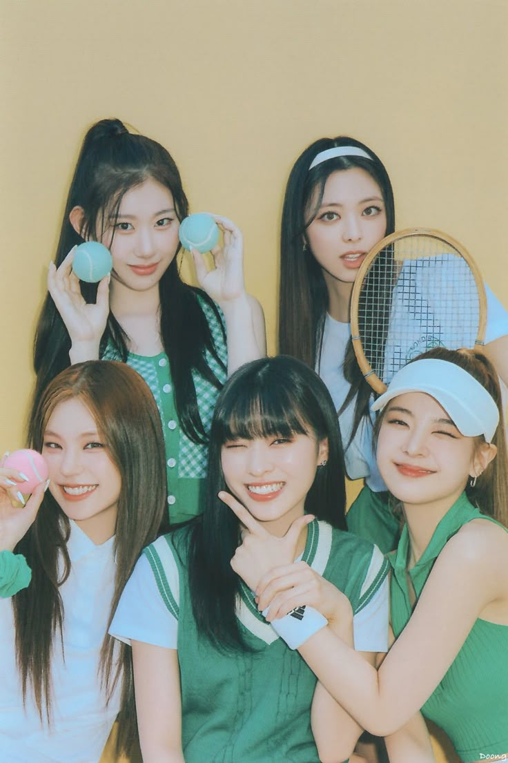 four girls are posing with tennis rackets and balls