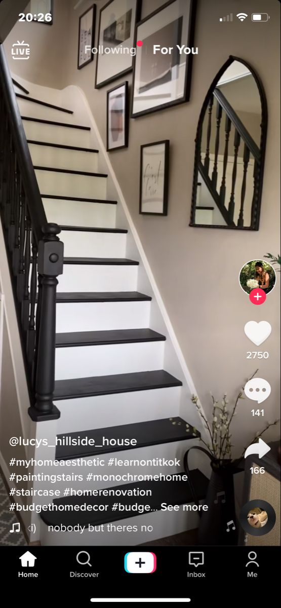 the stairs in this house are all black and white with pictures on the wall above them