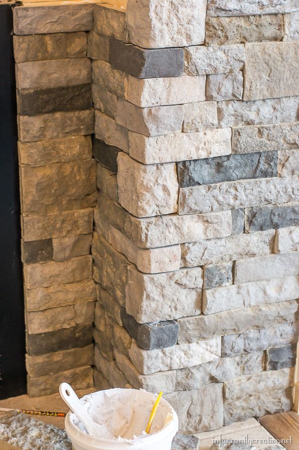 a bucket full of sand next to a stone fireplace with a fire place in the background