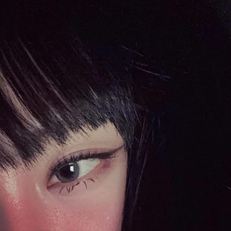 a close up of a person's eye with black hair