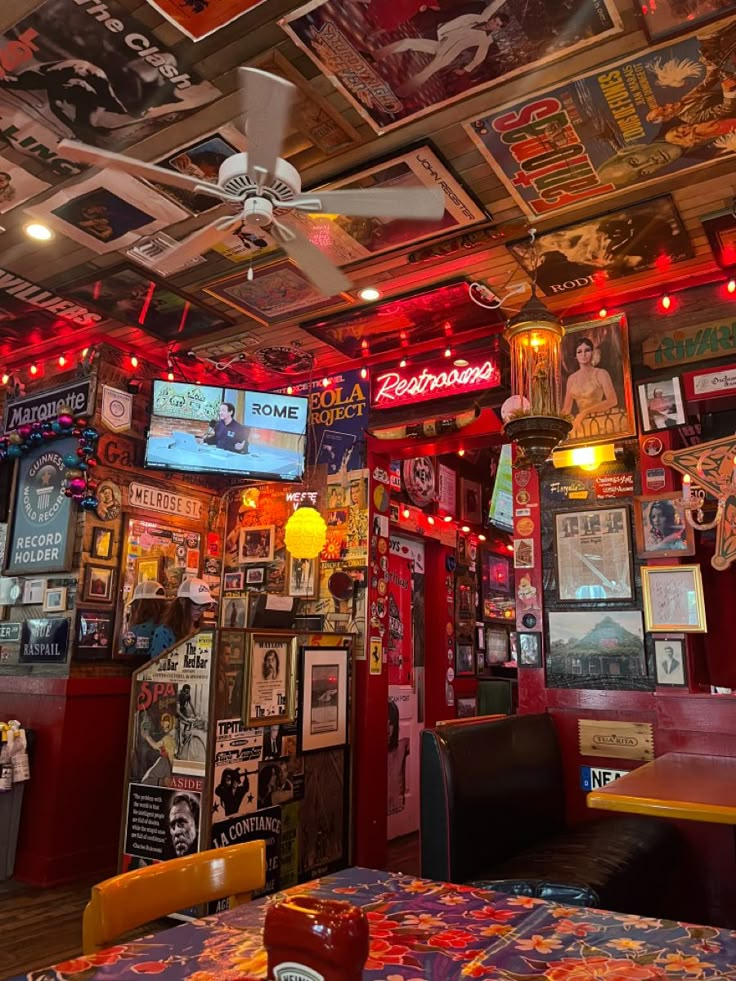 a room filled with lots of colorful signs and pictures on the ceiling above tables in front of tvs