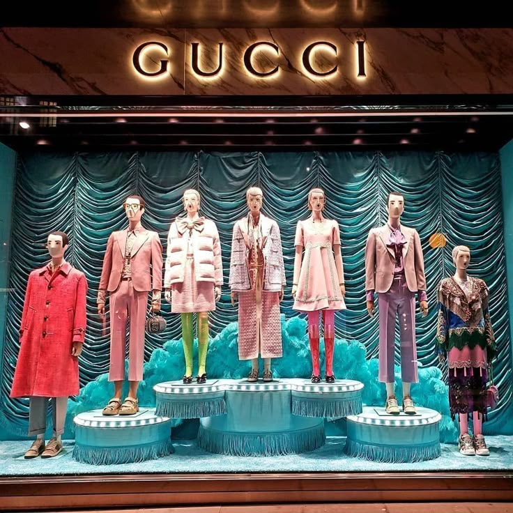 several mannequins are displayed in front of a gucci store display window